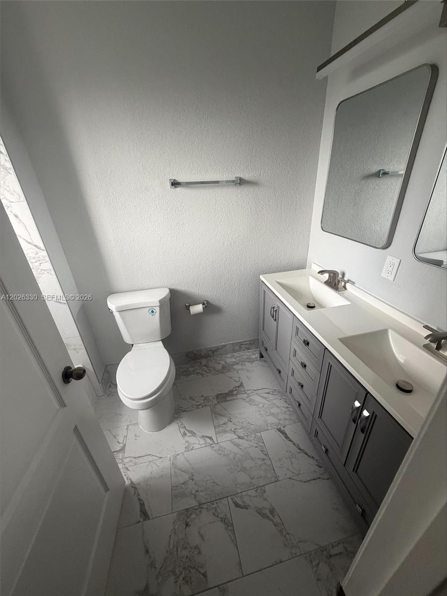 A bathroom features a double vanity with gray cabinets, marble-look tile flooring, and a toilet — 14773 SW 9th Ln # 0, Miami FL 33194, MIAMI, FL