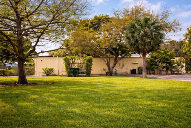 A grassy lawn sits in front of a long, beige building surrounded by mature trees — 2131 NE 48th Street, Lighthouse Point FL 33064, LIGHTHOUSE POINT, FL