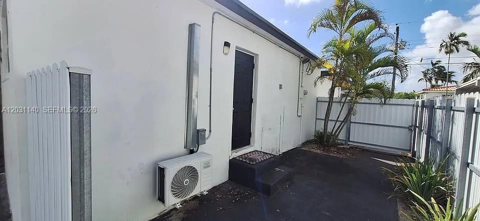 The exterior of a white building features a black door, an AC unit, and fencing — 7860 SW 17th St # A, Miami FL 33155, MIAMI, FL