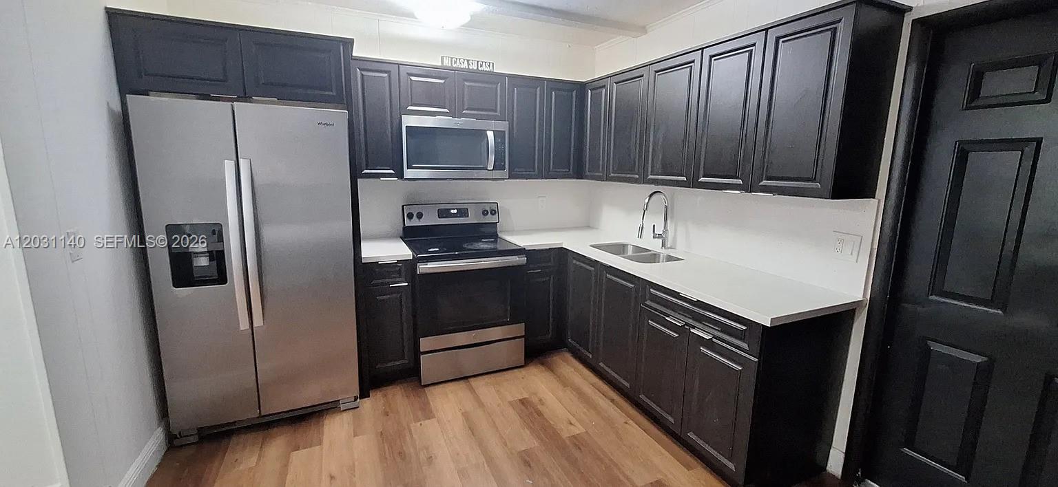 A kitchen features dark cabinets, stainless steel appliances, white countertops, and wood-look flooring — 7860 SW 17th St # A, Miami FL 33155, MIAMI, FL