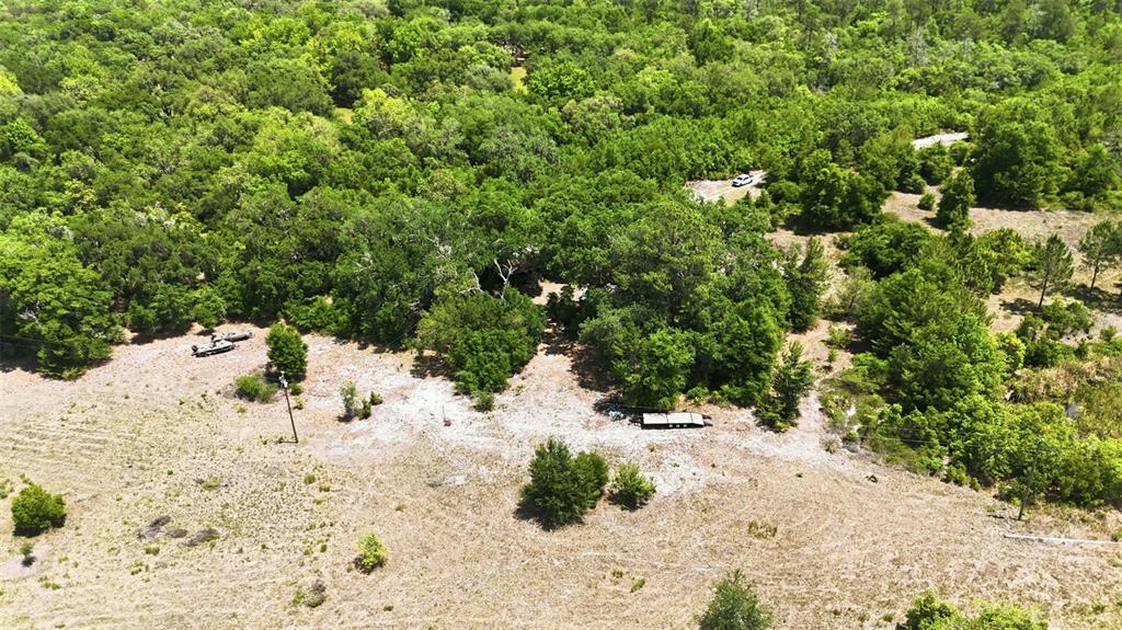 An aerial view shows a wooded lot with a cleared area, a trailer, and a boat — 16050 SE 275TH AVENUE, UMATILLA, FL