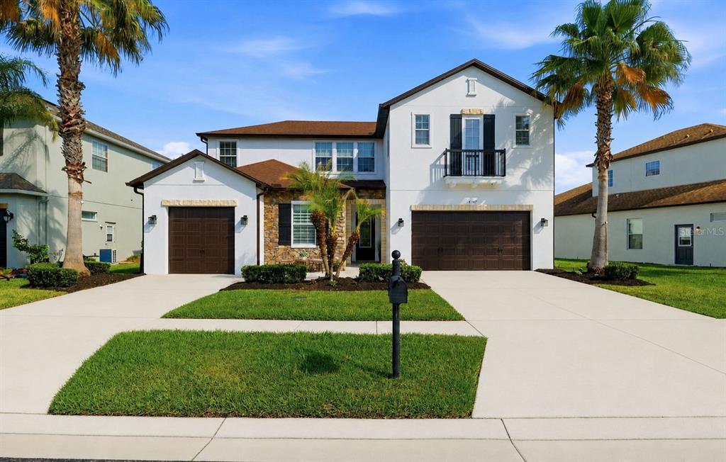 A two-story house with a white stucco exterior, brown roof, and two attached garages — 4107 WINDCREST DRIVE, WESLEY CHAPEL, FL