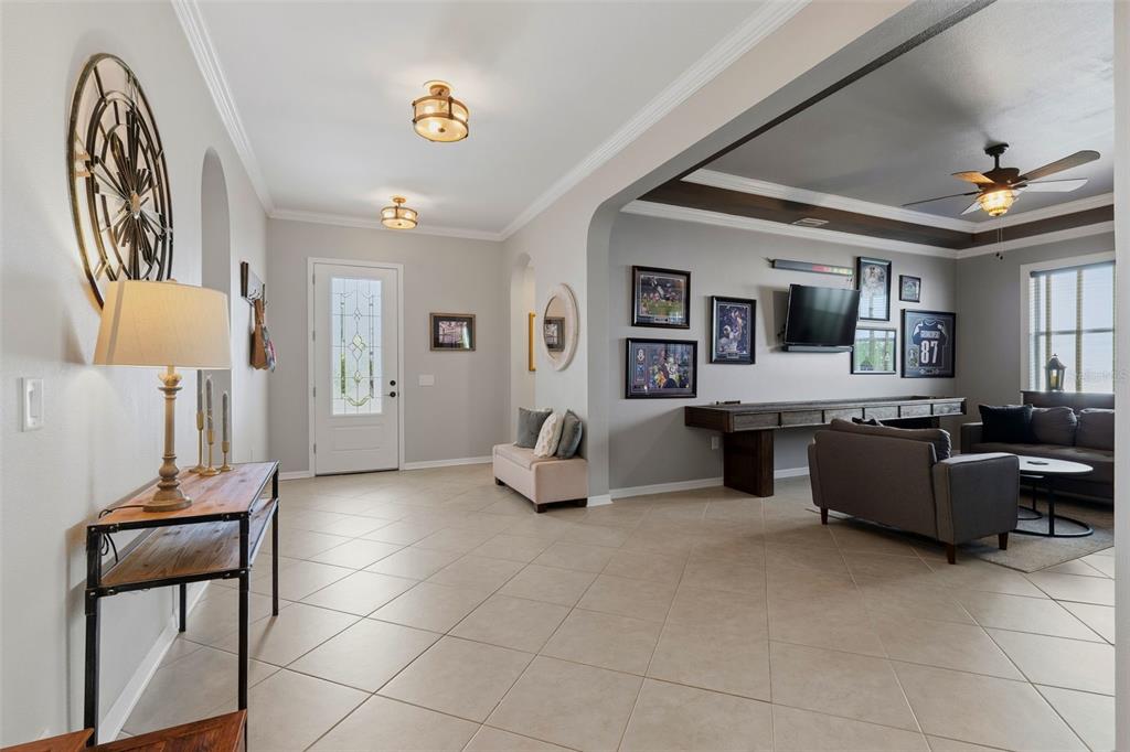 An open-concept living area features tile flooring, a console table, and a wall-mounted television — 4107 WINDCREST DRIVE, WESLEY CHAPEL, FL