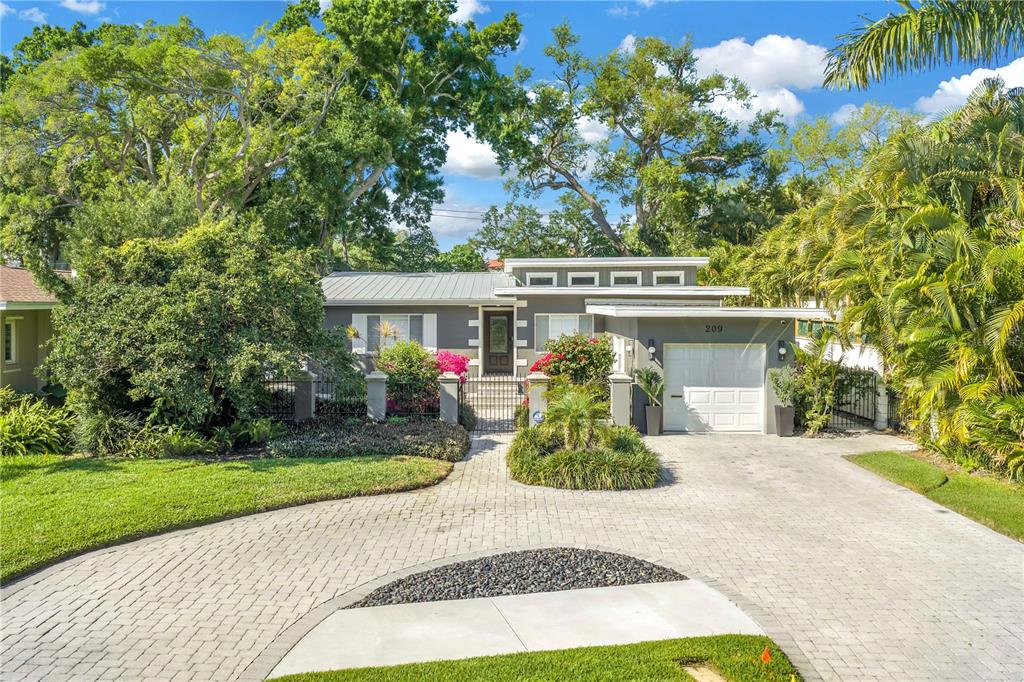 A single-story house with a gray exterior, metal roof, and a paved driveway — 209 BANDERA WAY NE, ST PETERSBURG, FL