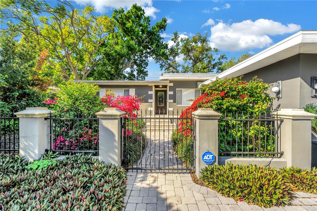 A paved walkway leads through a metal gate to the front entrance of a house — 209 BANDERA WAY NE, ST PETERSBURG, FL