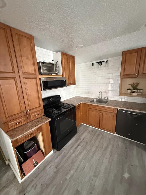 A kitchen features wood cabinets, a black stove, a dishwasher, and white subway tile backsplash — 2346 DRUID STREET UNIT 1616, CLEARWATER, FL