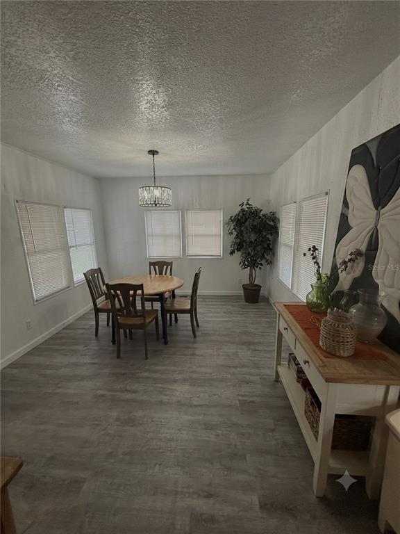 A dining room with gray wood-look flooring, a round wooden table, and a crystal chandelier — 2346 DRUID STREET UNIT 1616, CLEARWATER, FL