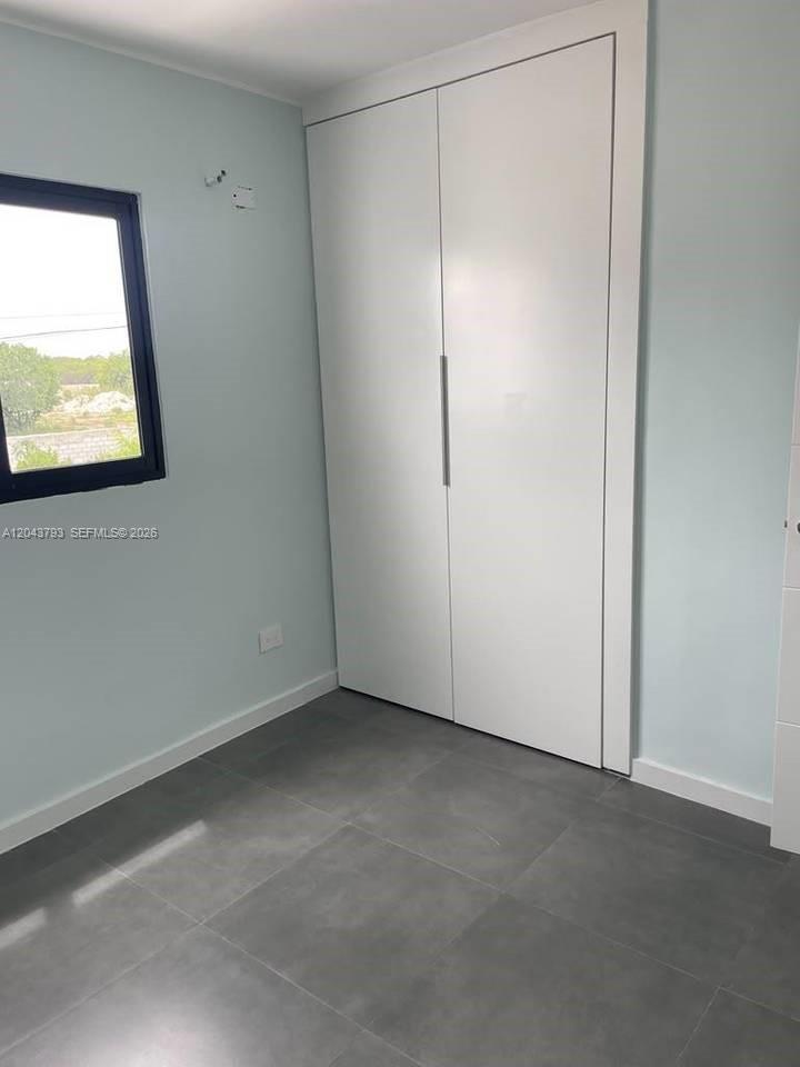 A room with light blue walls, gray tile flooring, and a white two-door closet — 0 residencial brisas, FL