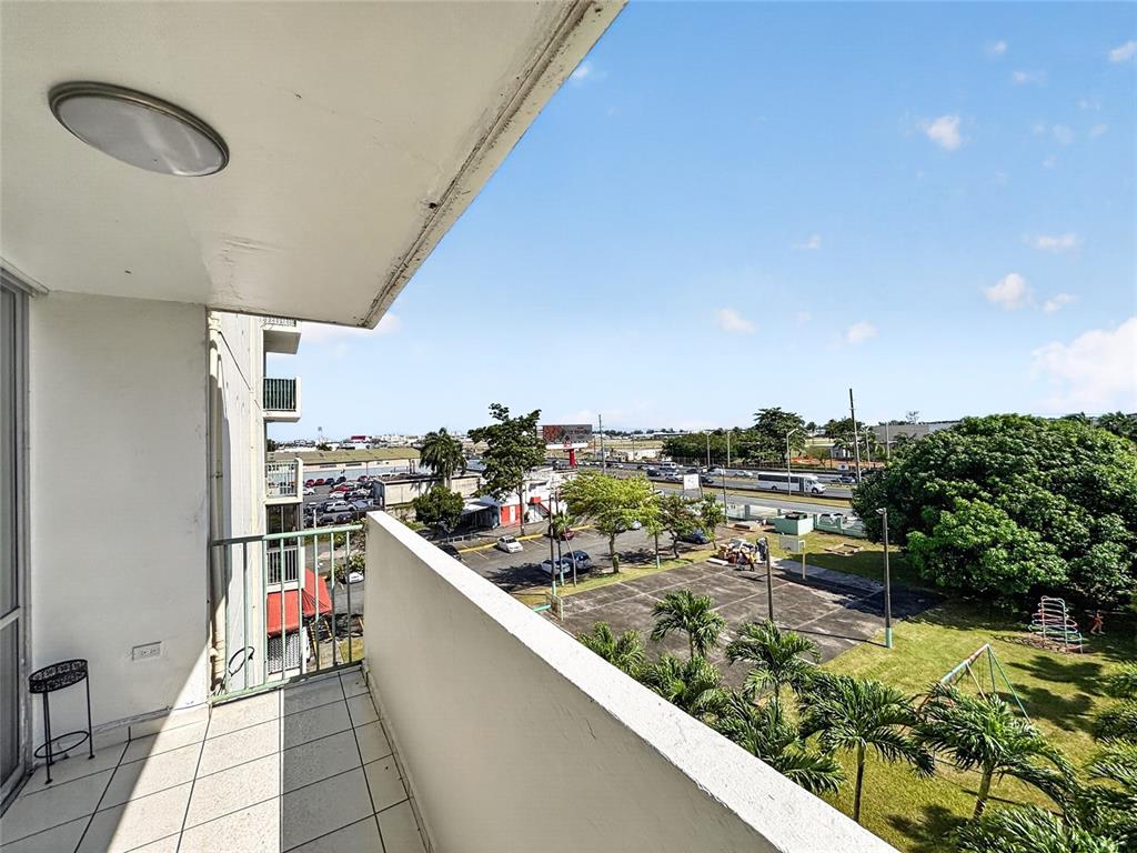 A high-angle view from a tiled balcony overlooking a parking lot, trees, and a highway — K CONDOMINIO INTERSUITES APT 5, CAROLINA, PR