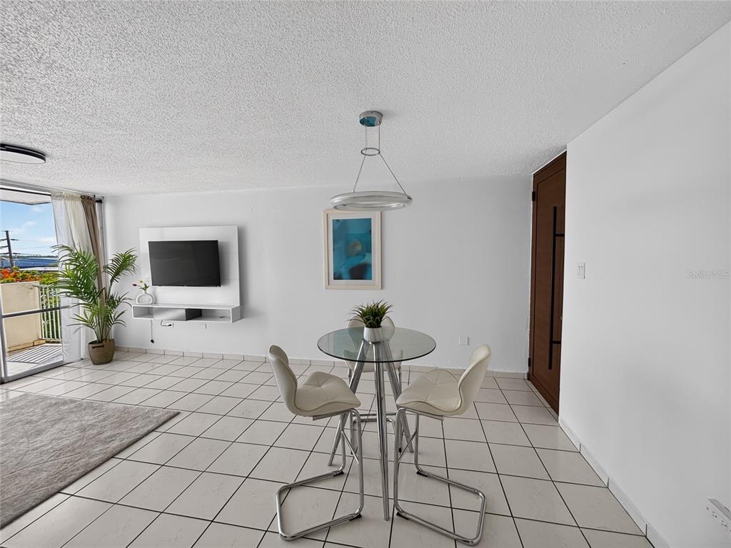 A dining area features a glass table, two chairs, and a pendant light on tile — K CONDOMINIO INTERSUITES APT 5, CAROLINA, PR
