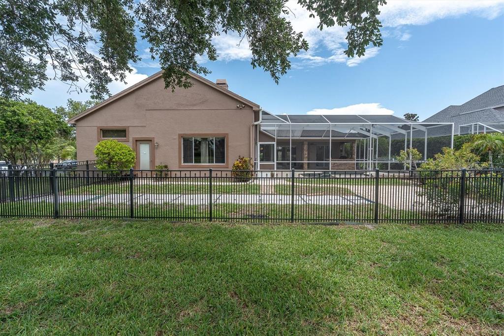 The exterior of a tan house features a screened-in patio and a black metal fence — 4270 COVE DRIVE, PALM HARBOR, FL