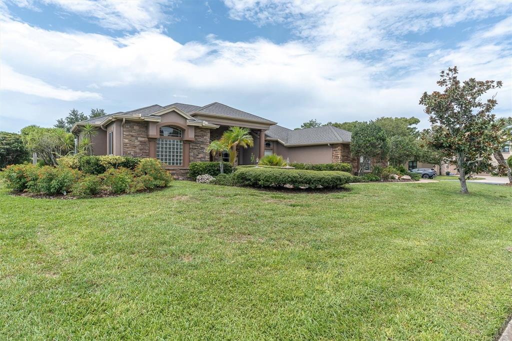 A single-story house with a stone facade, glass block window, and a large front lawn — 4270 COVE DRIVE, PALM HARBOR, FL
