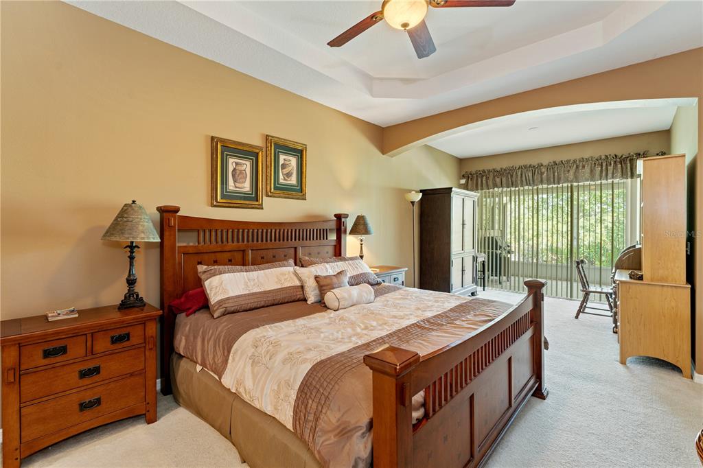 A bedroom features a wooden bed frame, matching nightstand, and a large sliding glass door — 19182 LAKE AUDUBON DRIVE, TAMPA, FL