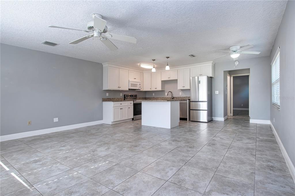 An open-concept kitchen features white cabinets, granite countertops, stainless steel appliances, and tile flooring — 301 ANDOVER PLACE S UNIT 170, SUN CITY CENTER, FL