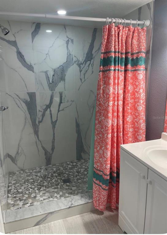 A bathroom features a walk-in shower with marble-look tile walls and a pebble floor — 5830 PORTSMOUTH DRIVE, TAMPA, FL