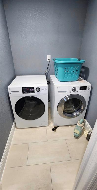 A laundry room features two white front-load washing machines and a blue plastic laundry basket — 5830 PORTSMOUTH DRIVE, TAMPA, FL