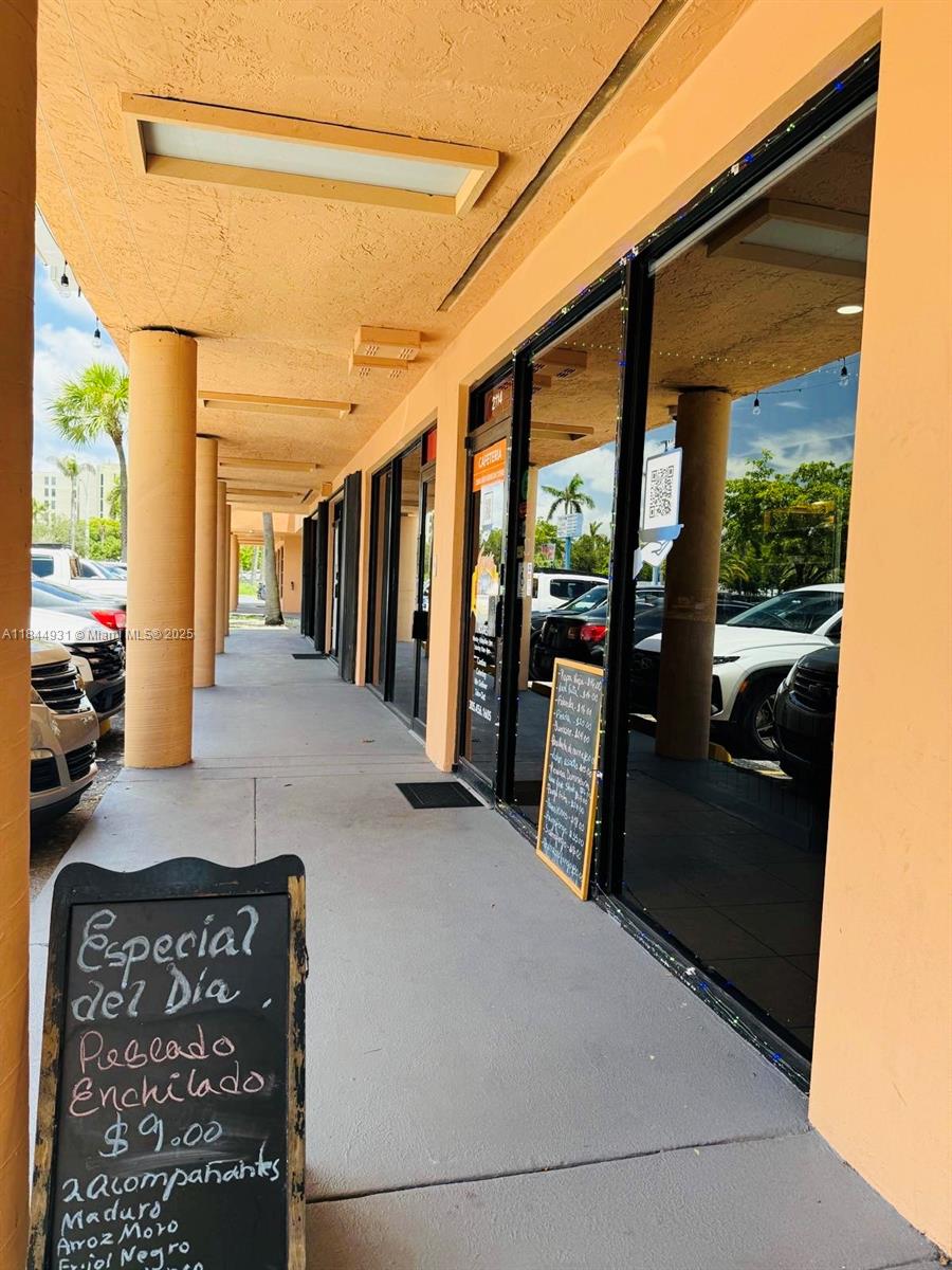 A sidewalk runs along the exterior of a commercial building with glass storefronts and signage — 2114 W 68 St, Hialeah FL 33016, HIALEAH, FL