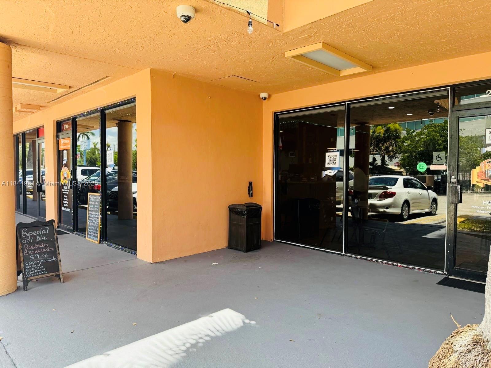The exterior of a commercial storefront features orange walls, glass doors, and a sidewalk — 2114 W 68 St, Hialeah FL 33016, HIALEAH, FL