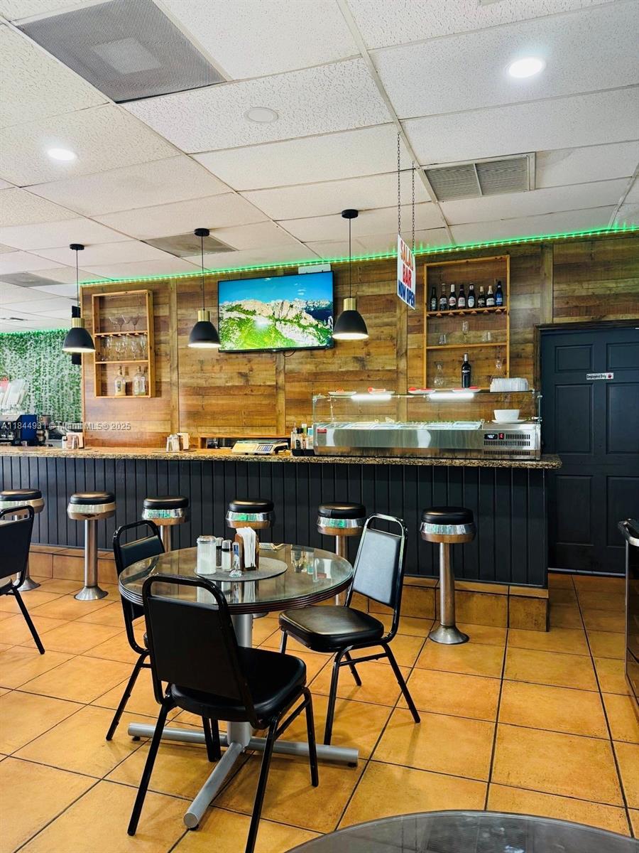 A restaurant interior features a bar with stools, a salad station, and dining tables — 2114 W 68 St, Hialeah FL 33016, HIALEAH, FL