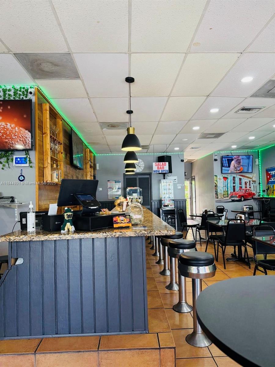 A restaurant interior features a granite-topped bar with stools, pendant lighting, and dining tables — 2114 W 68 St, Hialeah FL 33016, HIALEAH, FL