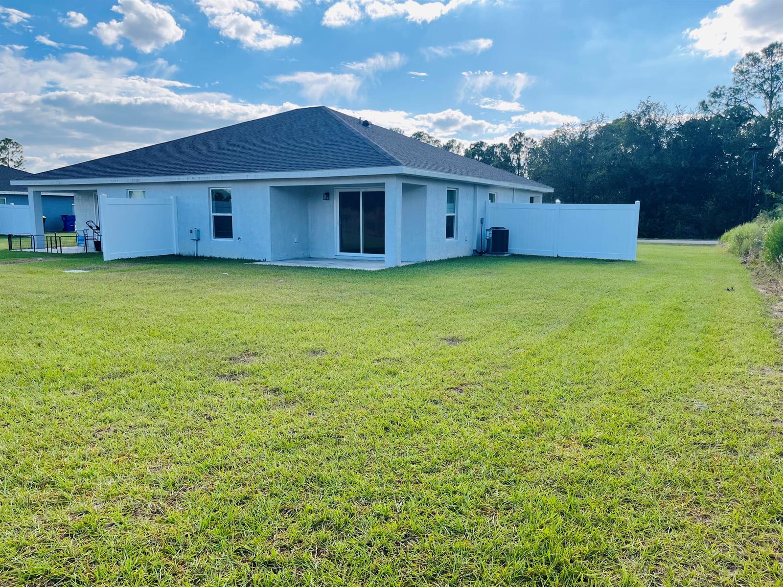 The exterior rear view of a single-story house with a white vinyl fence and lawn — 7056 San Benito Drive, Sebring FL 33872, SEBRING, FL