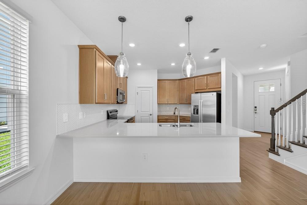 A kitchen with light wood cabinets, white countertops, and a breakfast bar island — 5807 PORTICO PLACE, KISSIMMEE, FL