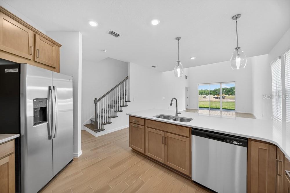 A kitchen with light wood cabinets, stainless steel appliances, and a white quartz island — 5807 PORTICO PLACE, KISSIMMEE, FL