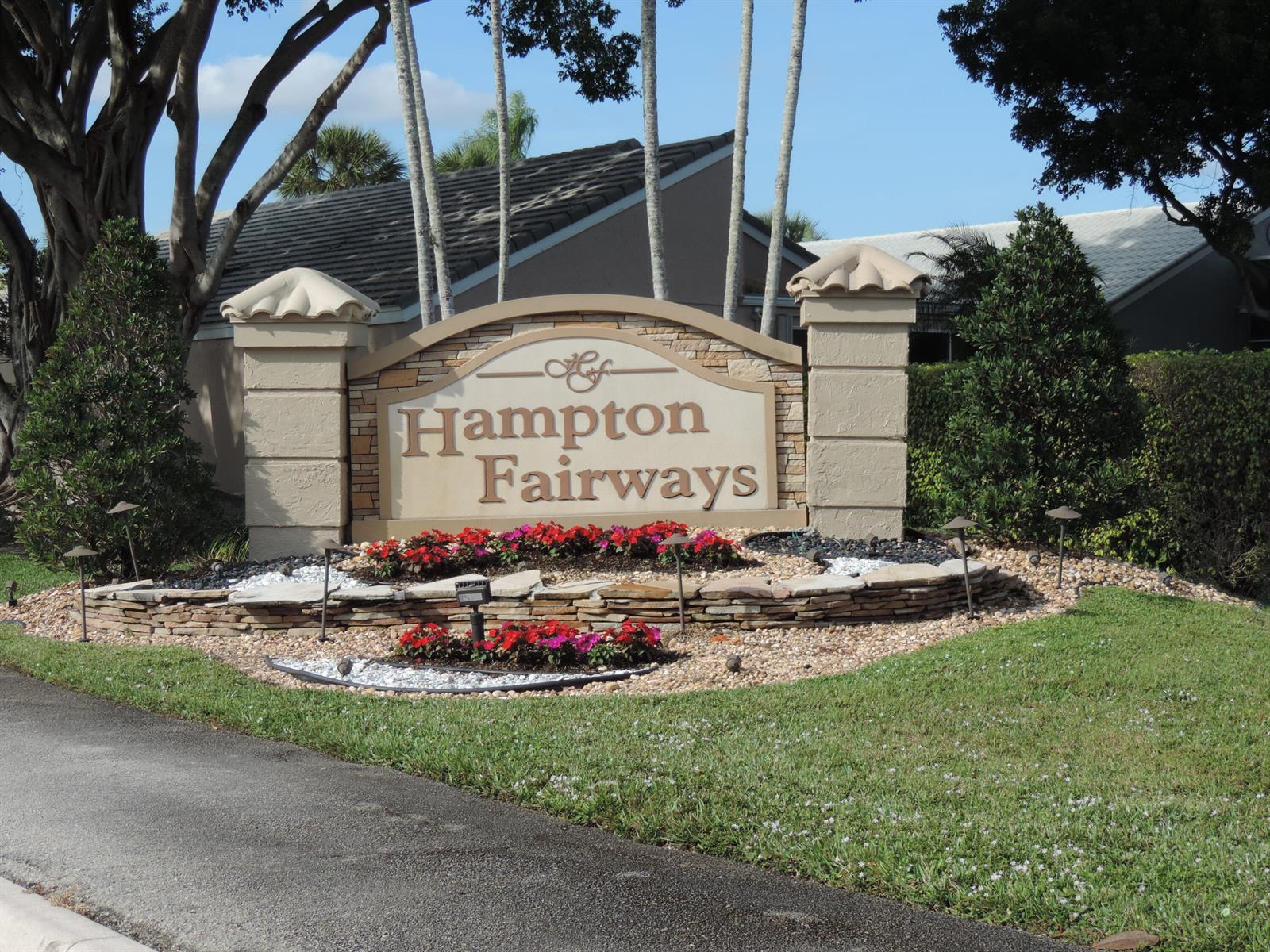 A stone monument sign for Hampton Fairways sits in a landscaped garden with flowering plants — 6375 Three Lakes Lane, Boynton Beach FL 33437, BOYNTON BEACH, FL