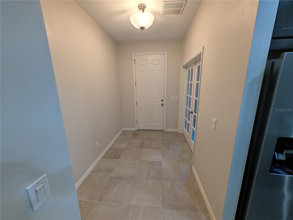 A tiled entryway features a white front door, a glass-paneled door, and a ceiling light — 2358 KENNINGTON COVE, DELAND, FL