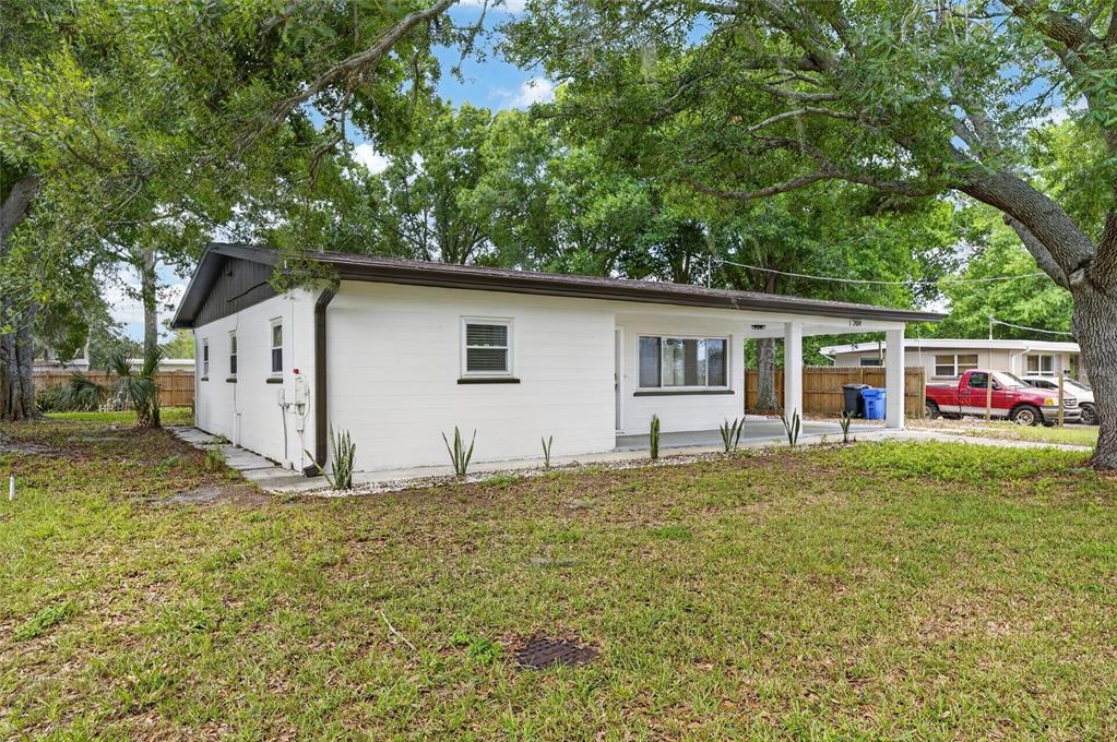 A white single-story house with a covered front porch sits on a grassy lot — 204 7TH AVENUE NW, RUSKIN, FL