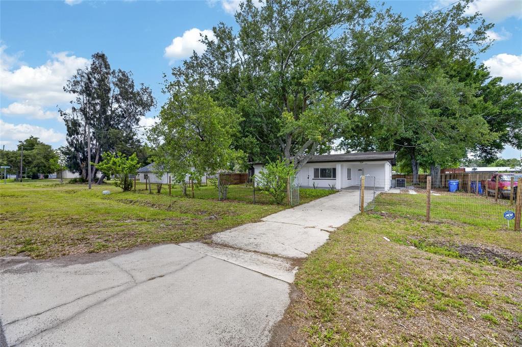A single-story house with a concrete driveway sits on a grassy lot with large trees — 204 7TH AVENUE NW, RUSKIN, FL