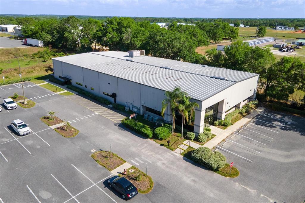 An aerial view of a commercial warehouse building with an adjacent parking lot and trees — 1904 THOMAS AVENUE UNIT 102, LEESBURG, FL