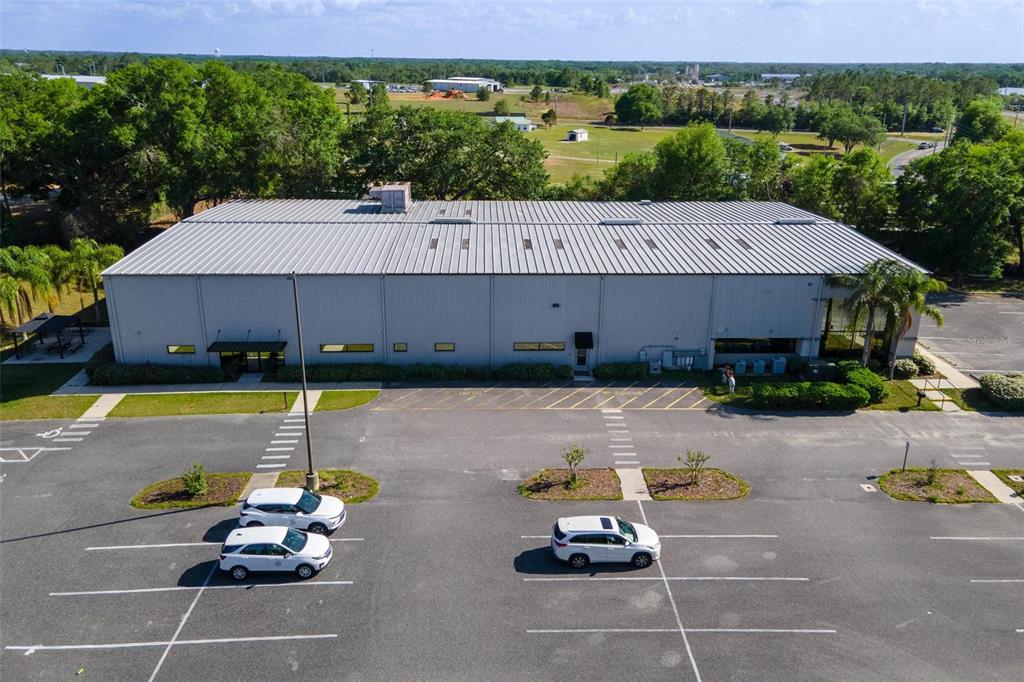 An aerial view shows a large metal-sided commercial building with a parking lot in front — 1904 THOMAS AVENUE UNIT 102, LEESBURG, FL
