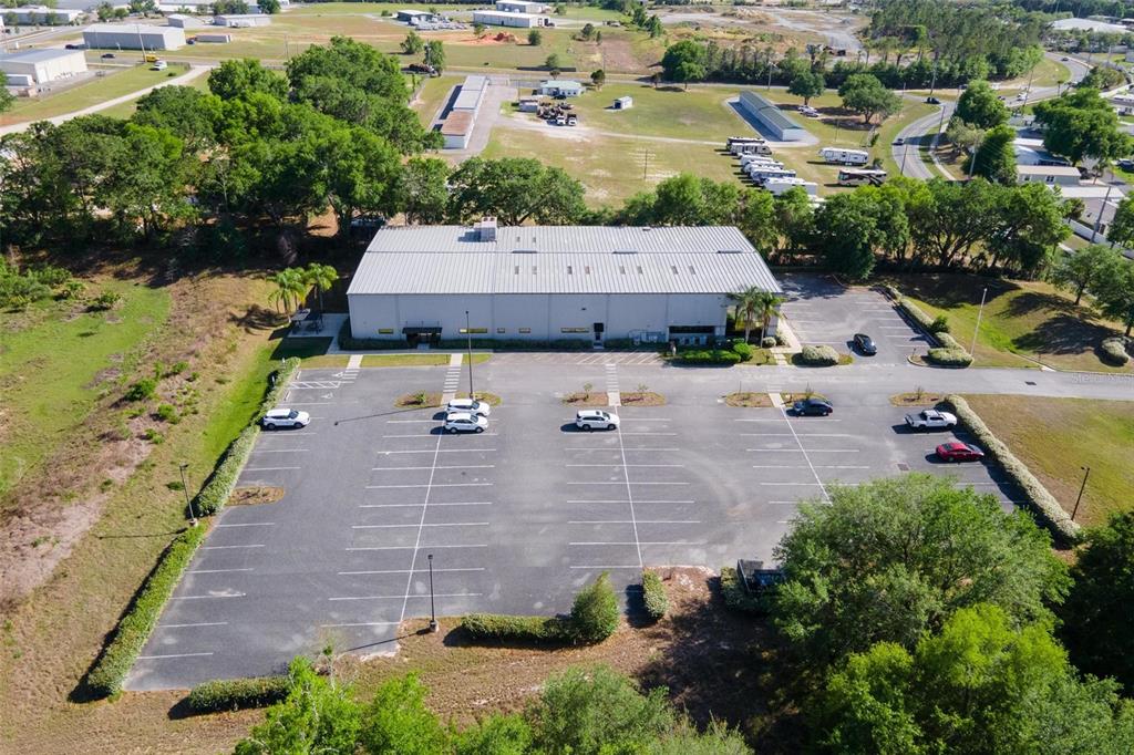 An aerial view shows a commercial building with a large parking lot and surrounding trees — 1904 THOMAS AVENUE UNIT 102, LEESBURG, FL
