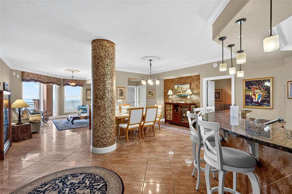 An open-concept living and dining area features tiled floors, a textured column, and ocean views — 3245 S ATLANTIC AVENUE UNIT 1002, DAYTONA BEACH SHORES, FL
