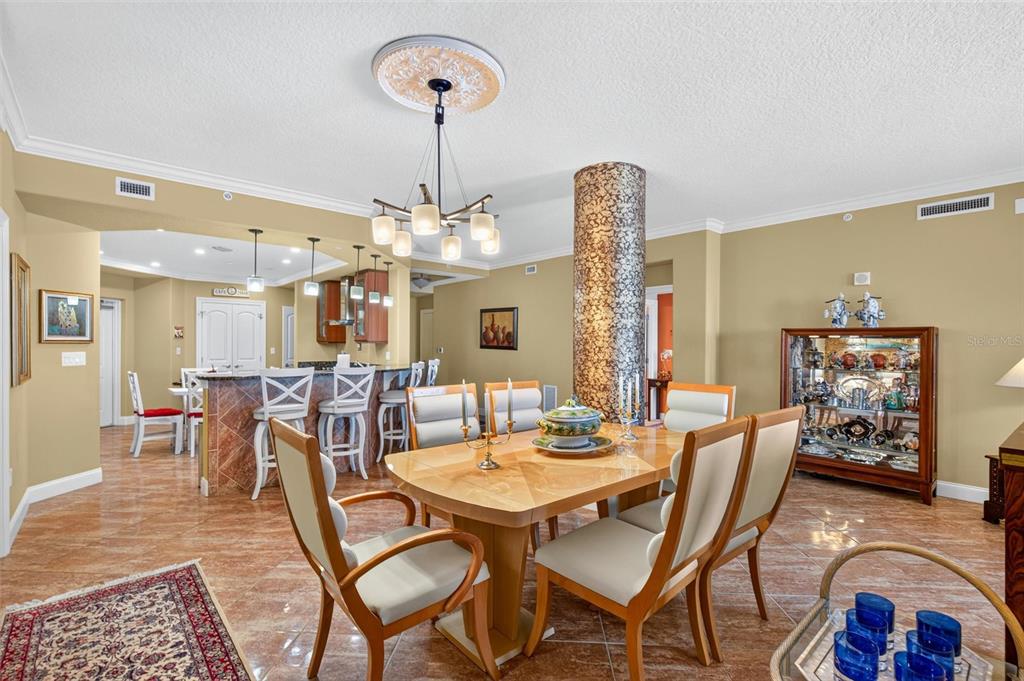 A dining area features a wooden table, chairs, a chandelier, and a decorative column — 3245 S ATLANTIC AVENUE UNIT 1002, DAYTONA BEACH SHORES, FL