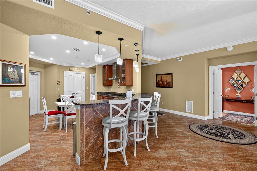 A kitchen with a granite-topped breakfast bar, white chairs, and tile flooring — 3245 S ATLANTIC AVENUE UNIT 1002, DAYTONA BEACH SHORES, FL