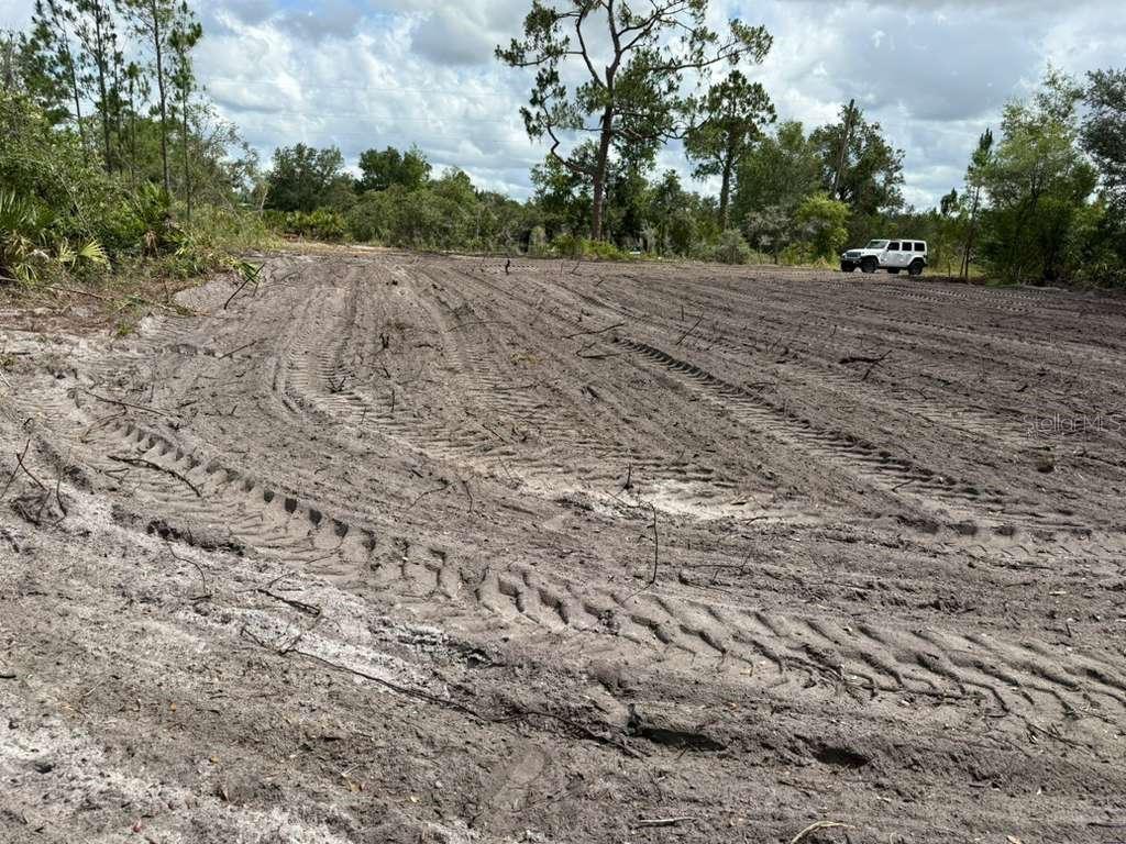 A cleared, dirt lot with tire tracks and a white vehicle parked in the distance — 3025 W METUCHEN ROAD, AVON PARK, FL