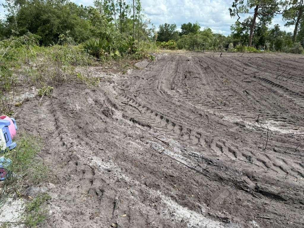 A cleared, muddy plot of land with tire tracks and surrounding trees under a cloudy sky — 3025 W METUCHEN ROAD, AVON PARK, FL