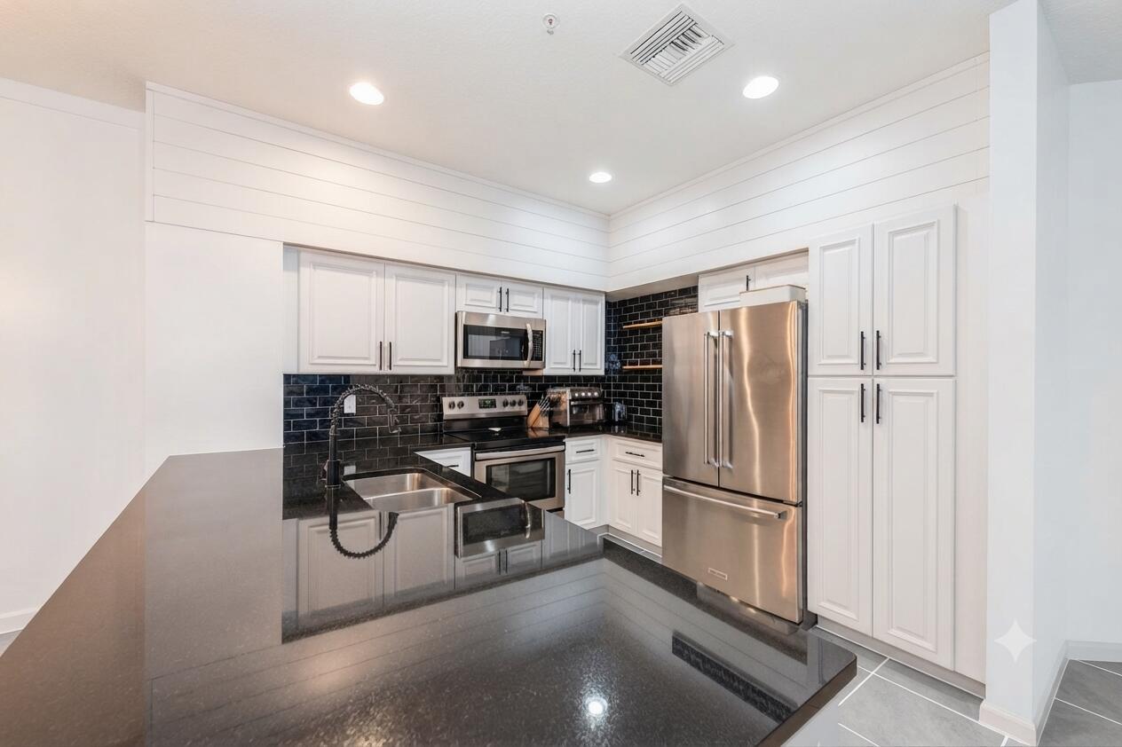 A kitchen features white cabinets, black subway tile backsplash, dark countertops, and stainless steel appliances — 4466 Leo Lane, Riviera Beach FL 33410, RIVIERA BEACH, FL