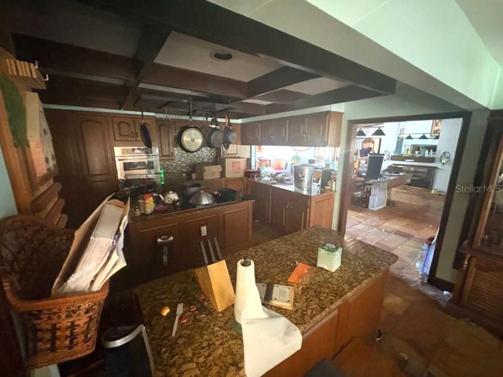 A kitchen with wood cabinets, a granite island, and a dark coffered ceiling — 122 FAIRWAY DRIVE, HAINES CITY, FL