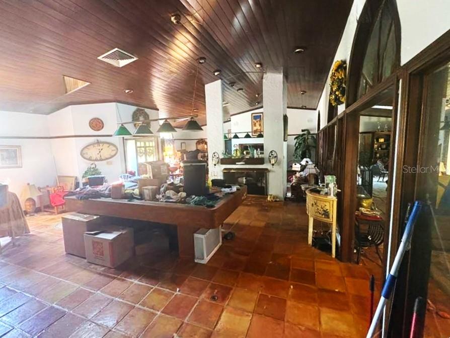 A room with a wood-paneled ceiling, tile flooring, and a large central pool table — 122 FAIRWAY DRIVE, HAINES CITY, FL