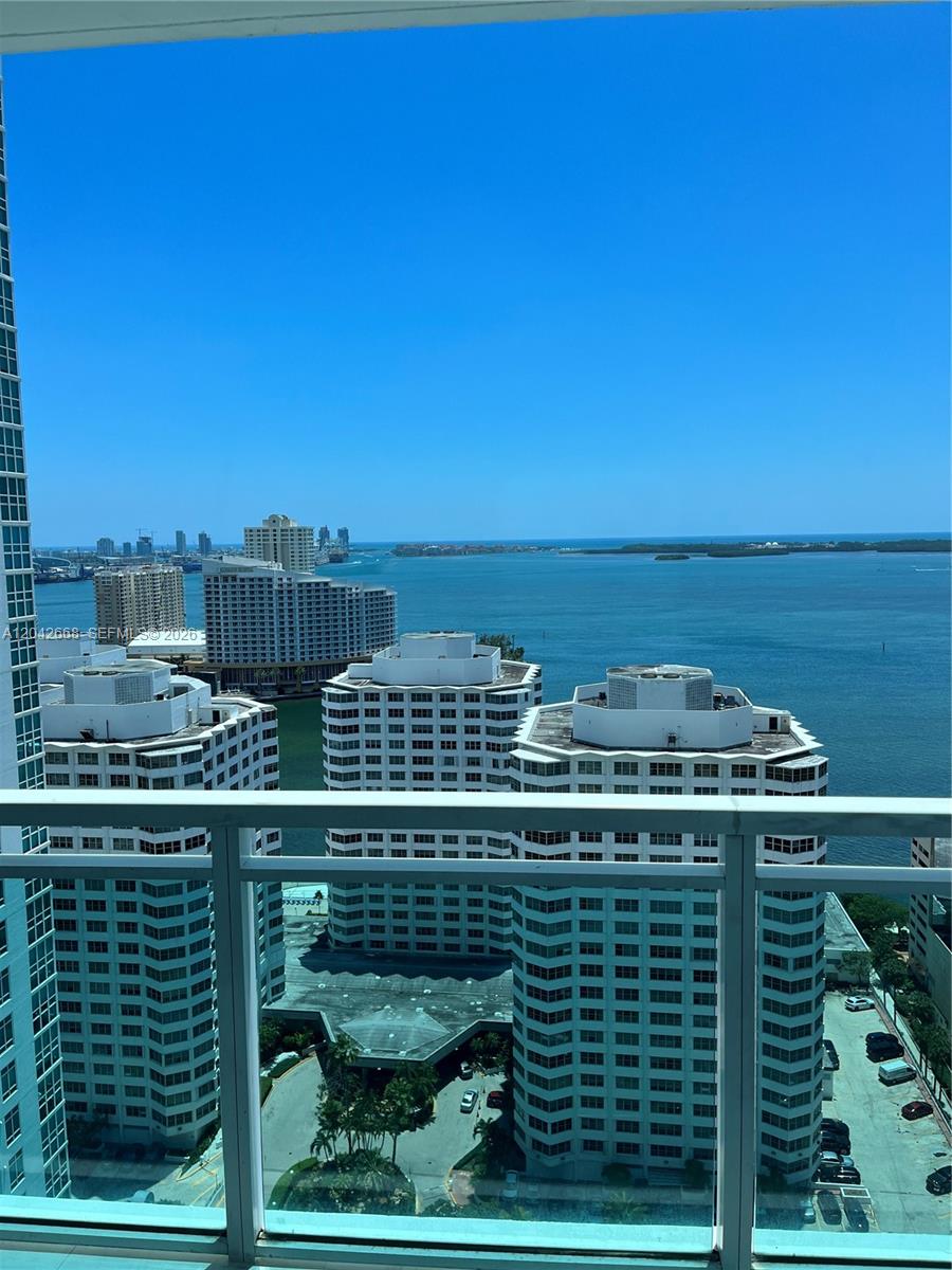 A high-angle view from a balcony overlooking several apartment buildings and the ocean — 951 Brickell Ave # 2704, Miami FL 33131, MIAMI, FL