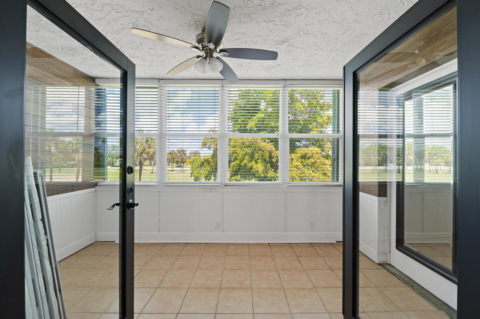 A sunroom with tile flooring, white wainscoting, and large windows overlooking a golf course — 7350 NW 18th Street # 207, Margate FL 33063, MARGATE, FL