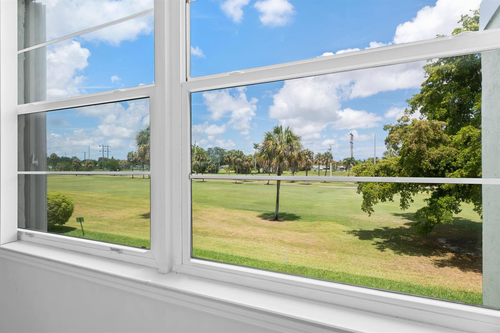 A view of a golf course through a white-framed window in a bright room — 7350 NW 18th Street # 207, Margate FL 33063, MARGATE, FL