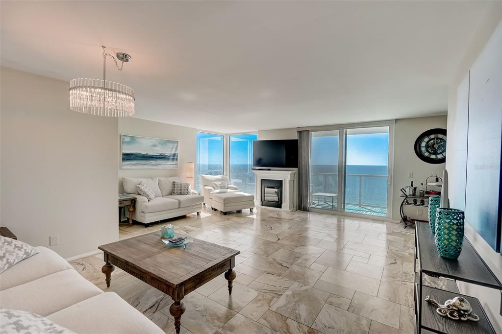 A living room features marble floors, a fireplace, and floor-to-ceiling windows overlooking the ocean — 2425 GULF OF MEXICO DRIVE UNIT 14B, LONGBOAT KEY, FL