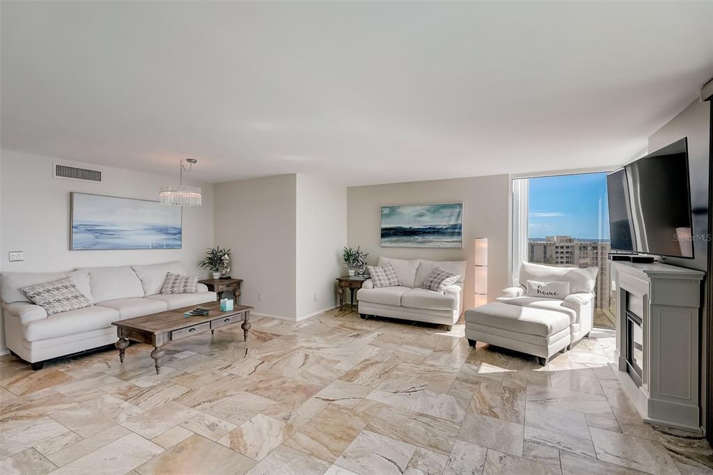 A bright living room features light-colored sofas, a wooden coffee table, and marble tile flooring — 2425 GULF OF MEXICO DRIVE UNIT 14B, LONGBOAT KEY, FL