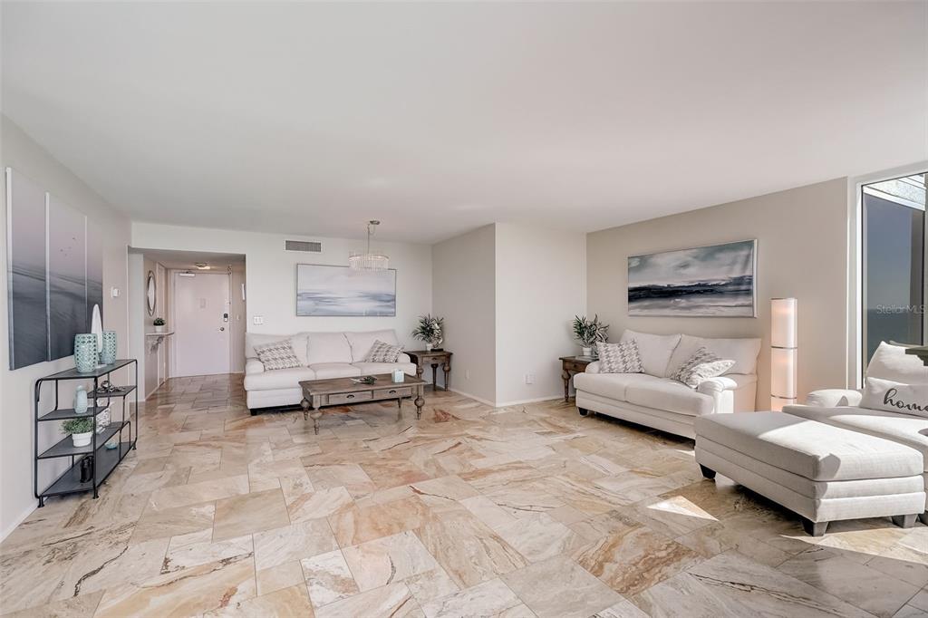 A spacious living room features light-colored sofas, a wooden coffee table, and stone tile flooring — 2425 GULF OF MEXICO DRIVE UNIT 14B, LONGBOAT KEY, FL