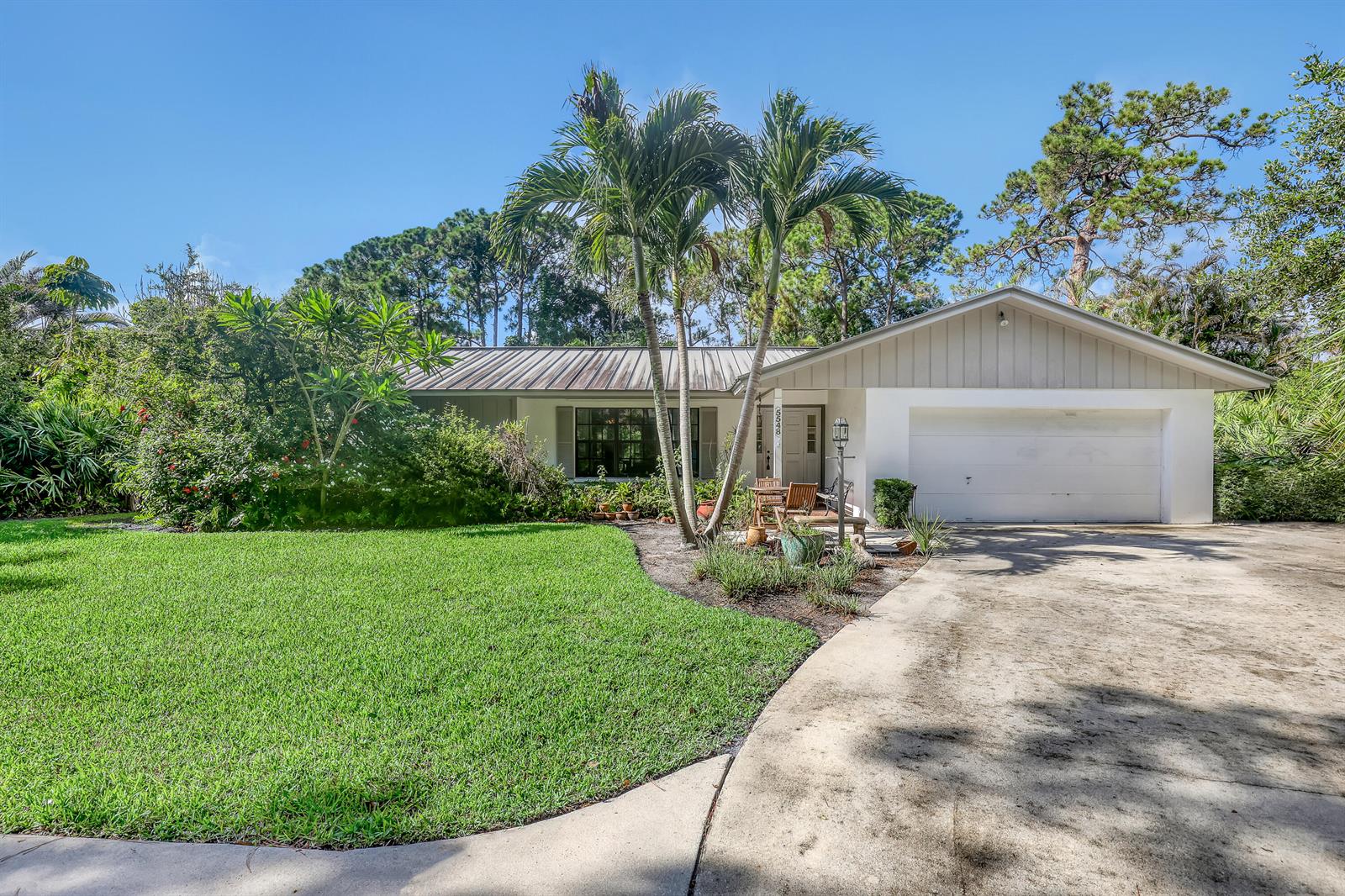 A single-story house with a white exterior, metal roof, palm trees, and a concrete driveway — 5548 Shirley Drive, Jupiter FL 33458, JUPITER, FL