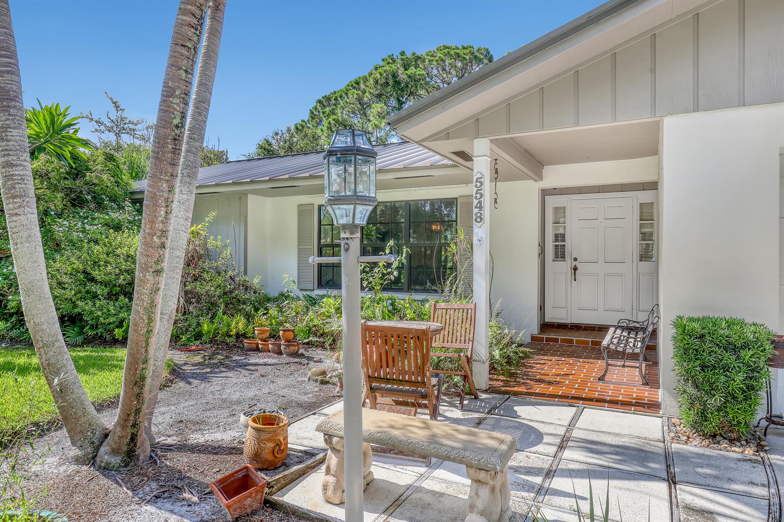 A single-story house exterior features a brick porch, a stone bench, and a lamp post — 5548 Shirley Drive, Jupiter FL 33458, JUPITER, FL